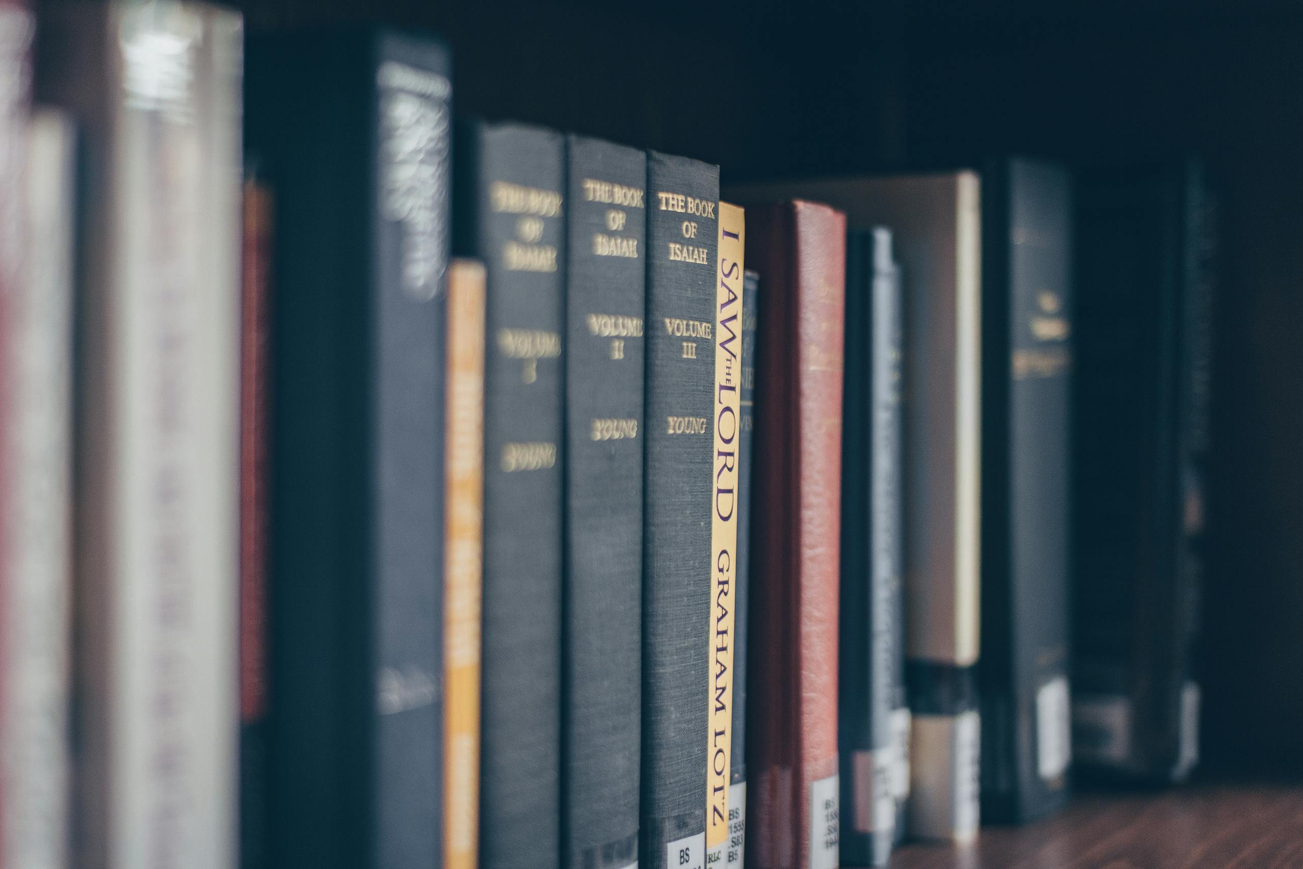 A focused view of books on a library shelf featuring various titles in soft lighting.